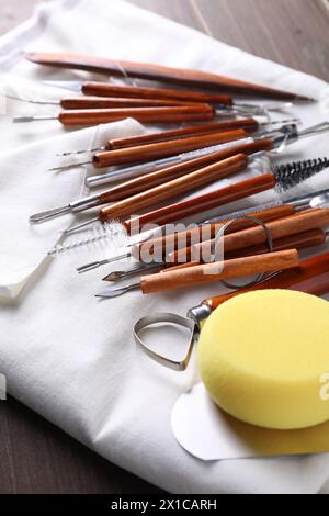 Set di diversi utensili per la lavorazione dell'argilla su tavolo in legno, primo piano Foto Stock