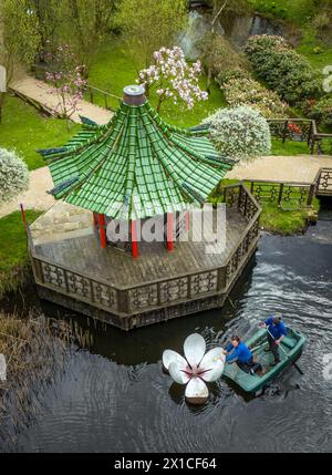 I giardinieri Joel Dibb e Kate Cannon utilizzano una piccola barca per installare "Magnolia", una scultura di Rebecca Newnham, nel lago Magnolia presso l'Himalayan Garden and Sculpture Park, vicino a Ripon, nel North Yorkshire. Data foto: Martedì 16 aprile 2024. Foto Stock