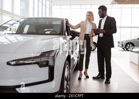 Donna d'affari di successo nello showroom di automobili per la vendita di veicoli ai clienti. Foto Stock