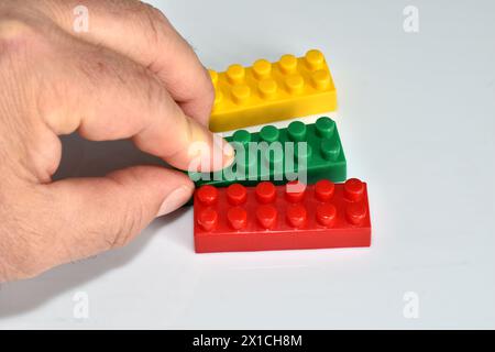 La mano di un uomo collegava tre parti colorate di un costruttore di bambini in una bandiera lituana. Foto Stock