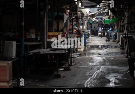 Bangkok, Thailandia - 11 aprile 2024 - l'atmosfera del mercato alimentare era chiusa a mezzogiorno e la signora anziana stava pulendo dopo la chiusura del mercato. Spazio Foto Stock