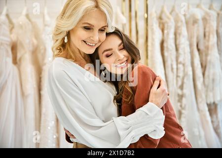 Due donne si abbracciano di fronte a un portabottiglie da sposa, una più giovane e l'altra più anziana, condividendo un momento speciale mentre acquistano l'abito perfetto. Foto Stock