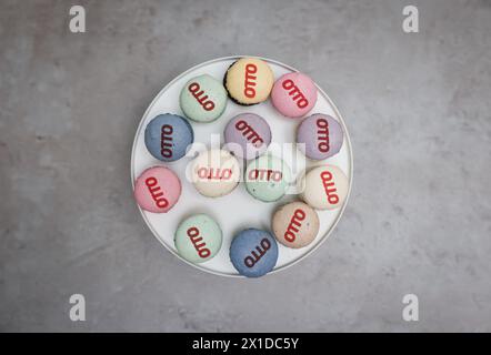 Amburgo, Germania. 16 aprile 2024. Un piatto di dolci macaron con il logo otto si erge su un tavolo in occasione dell'apertura della nuova sede di otto nel campus otto di Amburgo-Barmbek. L'ex edificio del magazzino, rinnovato e rivitalizzato, è stato aperto il martedì. Credito: Christian Charisius/dpa/Alamy Live News Foto Stock