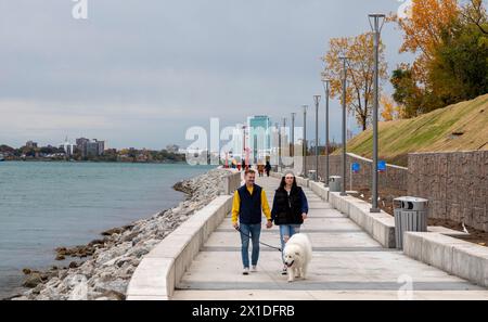 Detroit, Michigan - persone che camminano sul lungofiume di Detroit, sul sito della vecchia fabbrica di pneumatici Uniroyal. Foto Stock