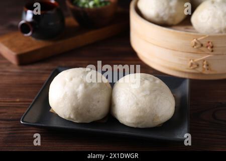 Deliziosi panini cinesi al vapore su un tavolo di legno, primo piano Foto Stock