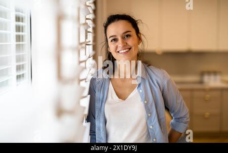 Ritratto di una bella giovane donna in piedi in cucina a casa Foto Stock