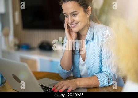 Ritratto di donna sorridente lavorando sul portatile a casa Foto Stock