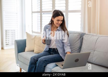 Ritratto di donna sorridente lavorando sul portatile a casa Foto Stock