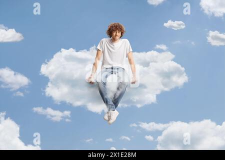 Ragazzo con capelli ricci che galleggia su una nuvola nel cielo Foto Stock