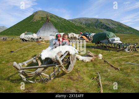 YAMAL, RUSSIA - 27 AGOSTO 2018: I bambini siedono in slitta in un insediamento di allevatori di renne Khanty nella soleggiata giornata estiva Foto Stock