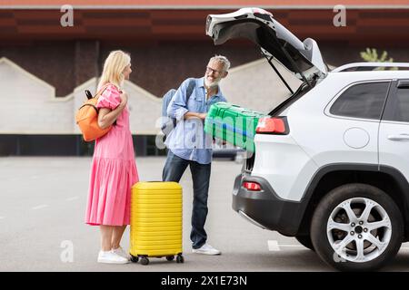 Coppia senior che carica i bagagli nel bagagliaio dell'auto Foto Stock