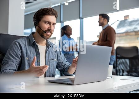 Uomo sorridente che lavora al call center al telefono con l'auricolare Foto Stock
