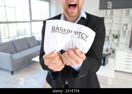Un uomo d'affari arrabbiato che sfrega la carta in ufficio. Concetto di fallimento Foto Stock