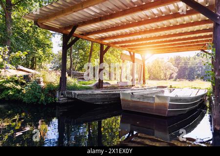 Vecchia barca in metallo ormeggiata sotto capannone riparo con baldacchino in legno rustico Boathouse nella campagna del canale Spreewald, casa della riserva della biosfera nazionale. Panoramica Foto Stock
