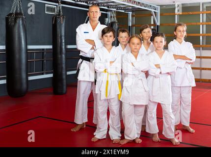 Bambini con il loro istruttore maschio che si pone in classe karate Foto Stock