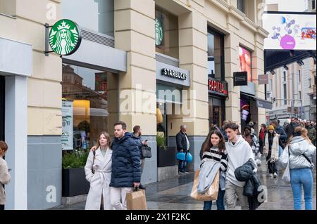 I pedoni passano davanti alla catena multinazionale americana Starbucks Coffee Store in una strada affollata in Spagna. Foto Stock