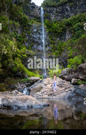 Descrizione: Turista femminile in abbigliamento sportivo guarda alla pittoresca cascata. Cascata Lagoa do vento, isola di Madeira, Portogallo, Europa. Foto Stock