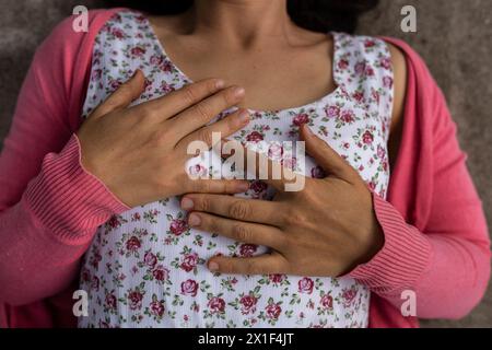 Vista dall'alto delle mani della giovane donna latinoamericana (33). Indossa un vestito fiorito e un maglione rosa. Non riconoscibile. Concetto primaverile. Foto Stock