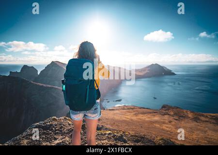 Descrizione: Vista posteriore di un turista che si trova in cima alle colline pedemontane di un'isola nell'Oceano Atlantico al mattino. São Lourento, Madeira I. Foto Stock