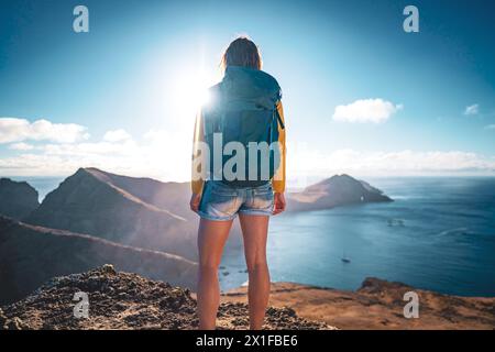 Descrizione: Visuale posteriore ad angolo basso di un turista che si trova in cima alle colline pedemontane di un'isola nell'Oceano Atlantico al mattino. São Lourenceo Foto Stock