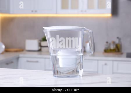 Caraffa con filtro dell'acqua su un tavolo in marmo bianco in cucina, primo piano Foto Stock