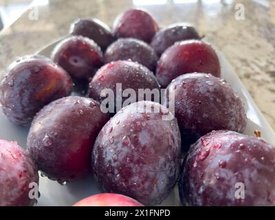 Prugne fresche su un piatto in un ambiente luminoso e moderno Foto Stock