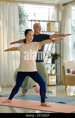 Coppia attiva e diversificata che pratica yoga a casa Foto Stock