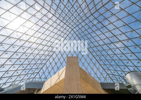 I pannelli geometrici di vetro della Piramide del Louvre, visti da sotto contro un cielo azzurro limpido a Parigi, con strutture interne visibili. Francia Foto Stock