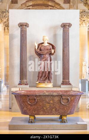 Donna in preghiera tra due colonne ioniche. Una donna in abito drappeggiato si erge in preghiera tra due colonne ioniche all'interno del Museo del Louvre, esponendo antichità classica. Parigi, Francia Foto Stock