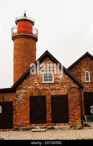 Un affascinante cottage in mattoni con un faro in legno arroccato sul suo tetto, che crea una facciata unica contro il cielo. Finestre, impianti e lavori in muratura Foto Stock