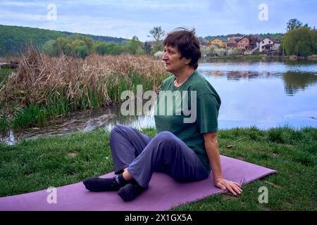 la vecchia donna che meditava la mattina sulla riva del fiume, veniva da casa in bicicletta Foto Stock