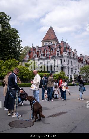 Un gruppo di giovani con un cane davanti allo Chateau d'Ouchy, un lussuoso hotel neogotico costruito in un castello del XII secolo sulle rive del Lago Gen Foto Stock