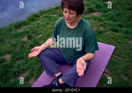 la vecchia donna che meditava la mattina sulla riva del fiume, veniva da casa in bicicletta Foto Stock