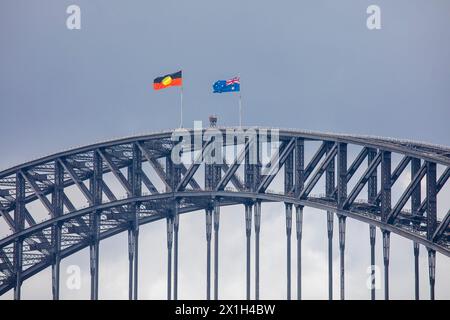 Inaugurato nel 1932, l'iconico Sydney Harbour Bridge sventola la bandiera nazionale australiana e la bandiera aborigena indigena Foto Stock