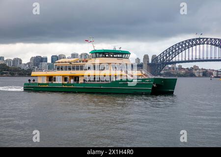 Il traghetto di Sydney, la MV Pemulwuy, viaggia sul porto di Sydney oltre il ponte del porto di Sydney, NSW, Australia, 2024 Foto Stock