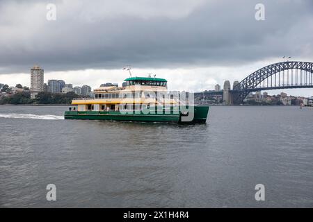 Il traghetto di Sydney, la MV Pemulwuy, viaggia sul porto di Sydney oltre il ponte del porto di Sydney, NSW, Australia, 2024 Foto Stock