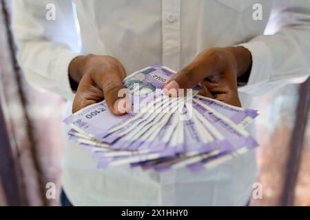 Primo piano delle mani di un uomo d'affari contando meticolosamente pile di banconote da 100 rupie in una scrivania pulita e organizzata in un ufficio moderno. Foto Stock