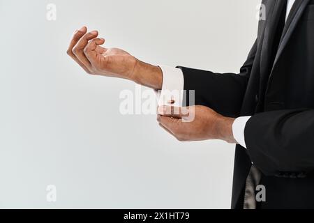 Uno sposo afroamericano giovane e affascinante con un abito che si estende la mano per una stretta di mano in uno studio su uno sfondo grigio. Foto Stock
