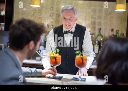 Barman che serve cocktail a una giovane coppia in un bar Foto Stock