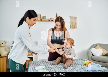 Una giovane e bella madre culla con amore il suo bambino in grembo, mentre riceve la guida del suo allenatore in un corso per i genitori. Foto Stock