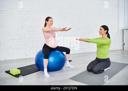 una donna incinta, guidata dal suo allenatore, esegue esercizi sulle palle durante una sessione di fitness prenatale. Foto Stock