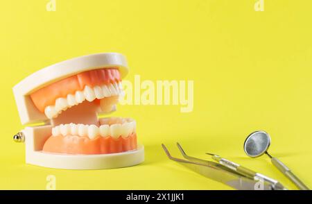 strumento dentale su sfondo giallo vicino a un mock-up della mascella dentale. Il concetto di malattia e trattamento dentale in odontoiatria. Parodontite e gengivi Foto Stock