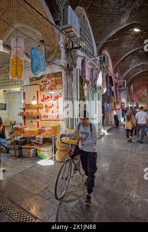 Un giovane cammina con la sua bicicletta in uno stretto passaggio nel Grand Bazaar di Isfahan, Iran. Foto Stock