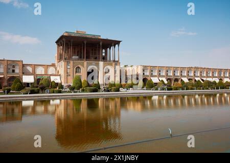 Vista del Palazzo Ali Qapu e degli edifici adiacenti riflessi in una piscina d'acqua in Piazza Naqsh-e Jahan, sito patrimonio dell'umanità dell'UNESCO. Isfahan, Iran. Foto Stock