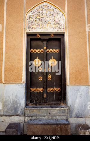 Porta d'ingresso chiusa di una casa tradizionale persiana con due battitori separati - barra di metallo per uomini e anello di metallo per donne. Isfahan, Iran. Foto Stock