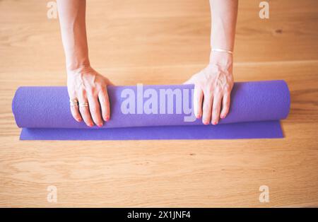 Donna irriconoscibile Yogi rotola il tappeto con le mani Foto Stock