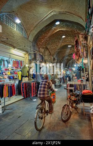 Un uomo corre in bicicletta in uno stretto passaggio nel Grand Bazaar di Isfahan, Iran. Foto Stock