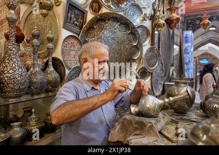 Qalamzani, o Ghalamzani (arte tradizionale iraniana dell'incisione del metallo), opera nel suo negozio di artigianato nel Grand Bazaar. Isfahan, Iran. Foto Stock