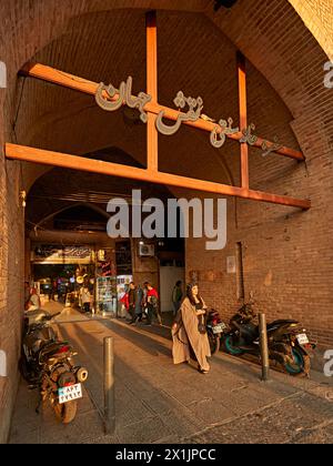 La giovane donna iraniana cammina in un passaggio ad arco dal Grand Bazaar a Piazza Naqsh-e Jahan, sito patrimonio dell'umanità dell'UNESCO. Isfahan, Iran. Foto Stock