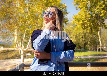 Giovane donna che si rilassa e si gode il sole in un parco caldo al tramonto. Foto Stock